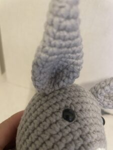 a hand holding a knitted grey dumb