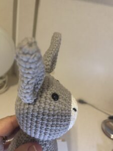 a hand holding a knitted grey dumb