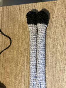 a pair of crocheted arms on a wood surface