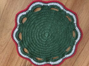 a green and white knitted doily on a wood surface